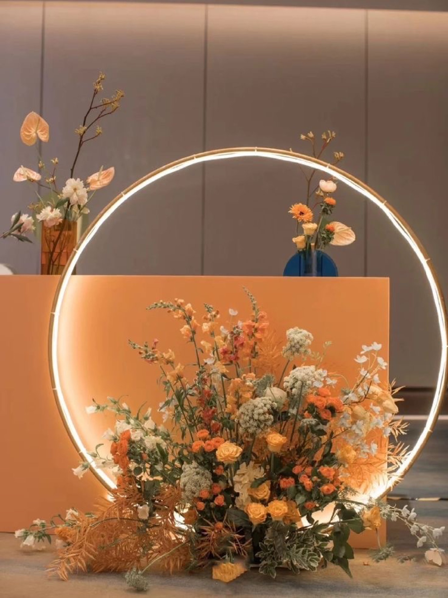 A lit circular ring installation with a warm orange floral arrangement